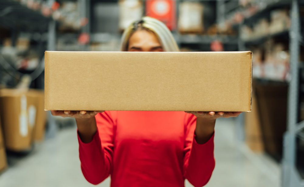 Woman in logistics warehouse with package